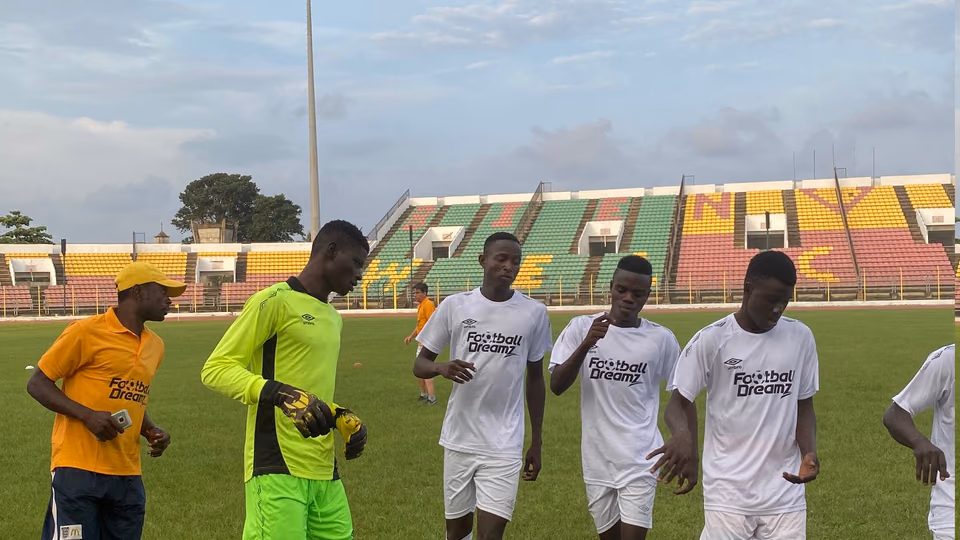 Young players in Football Dreamz shirts crossing a pitch with a coach after a trial