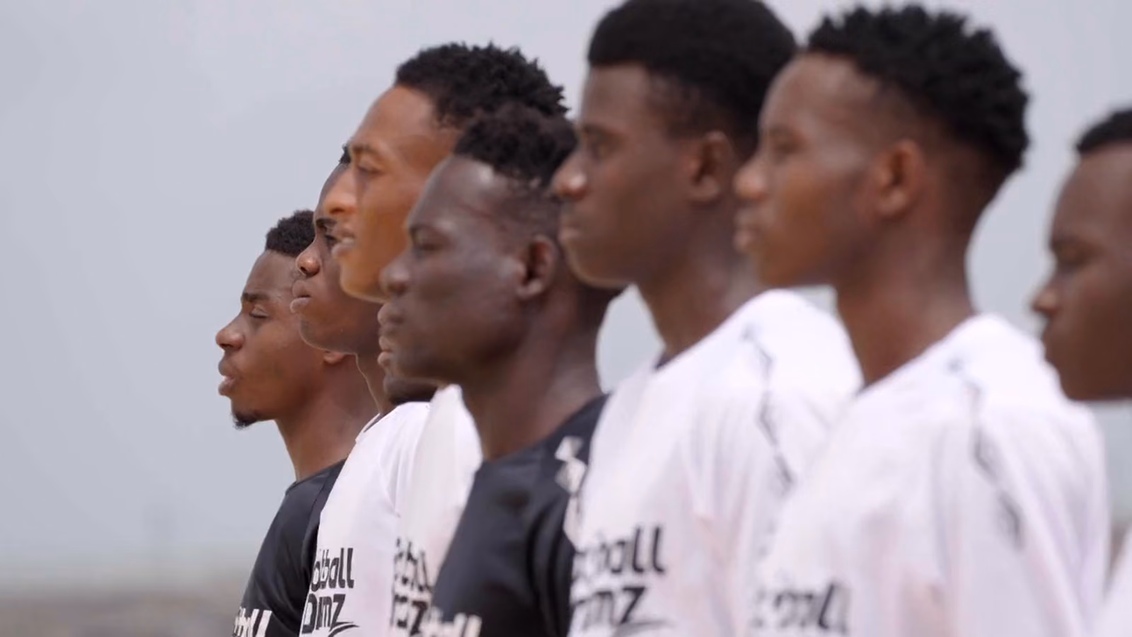 A line of players in Football Dreamz shirts on a pitch, waiting for a trial to start