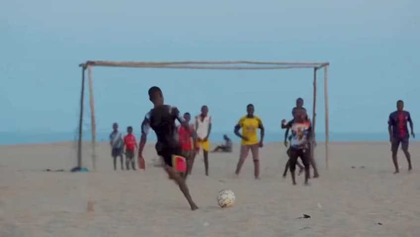 A line of players against the sea on a beach pitch, from the Football Dreamz film