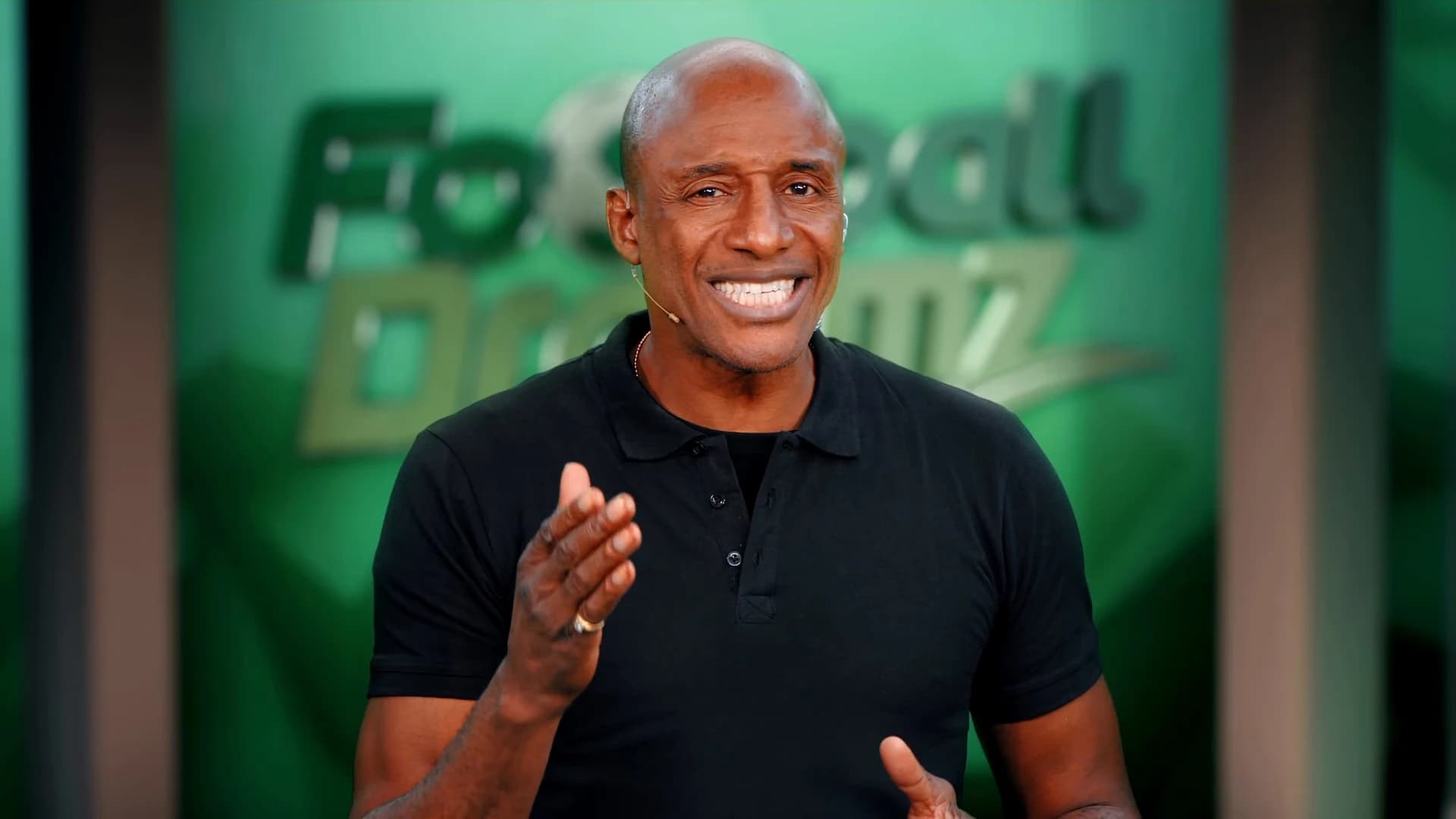 The presenter speaking to camera in front of a Football Dreamz backdrop