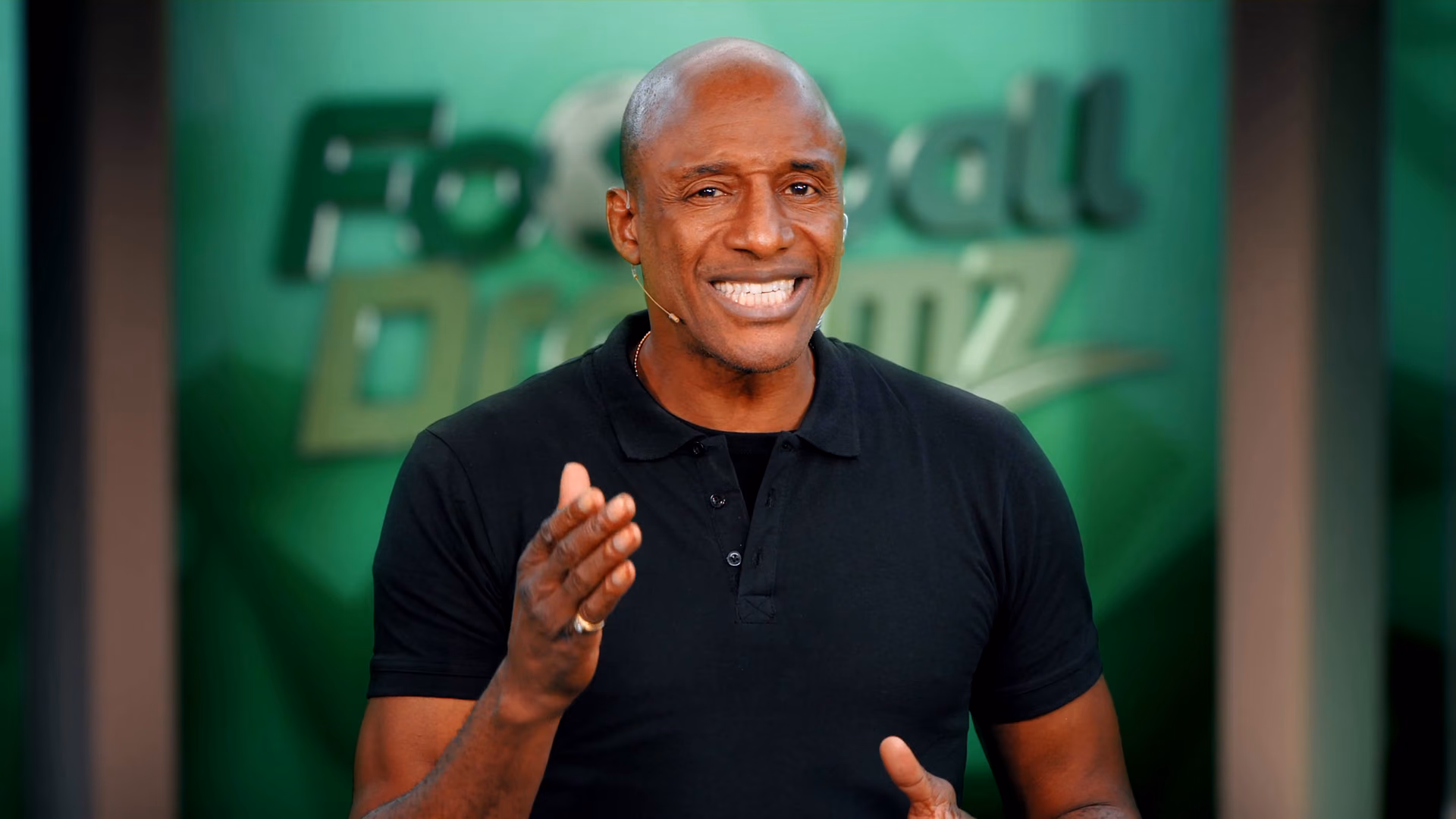 The presenter speaking to camera in front of a Football Dreamz backdrop