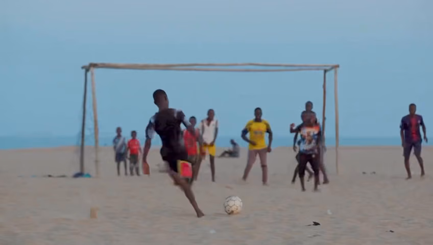 A line of players against the sea on a beach pitch, from the Football Dreamz film
