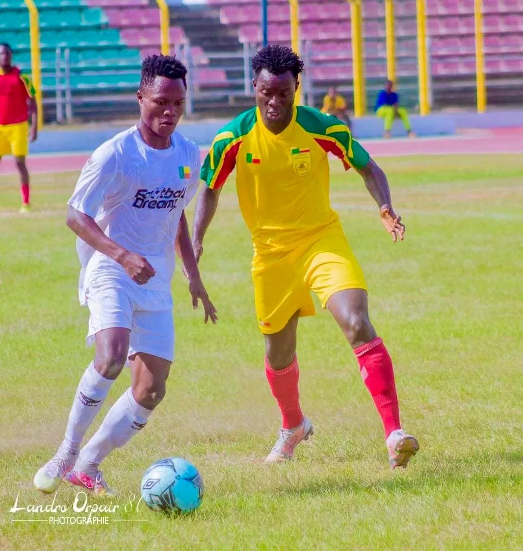 A Football Dreamz player on the ball with a Benin defender closing in