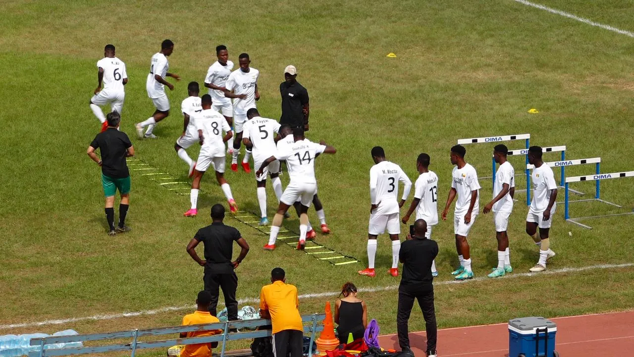 Players in white working through a ladder drill beside training hurdles