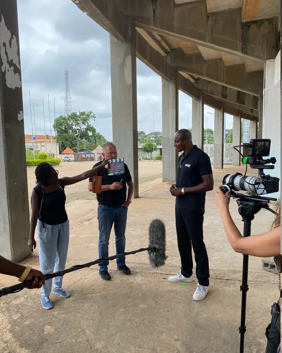 Crew filming presenter John Fashanu, clapperboard in shot