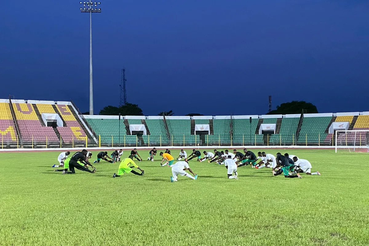 Squad stretching on the pitch at dusk